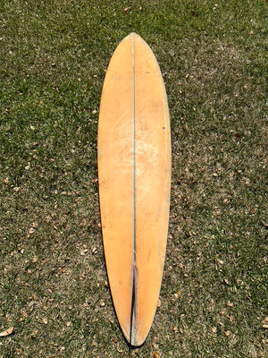 Wooden surfboard lying on a grassy surface