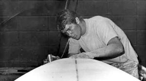 Person working on a surfboard in a workshop setting