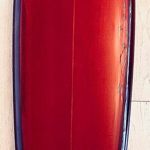 Red surfboard with a logo on a wooden floor