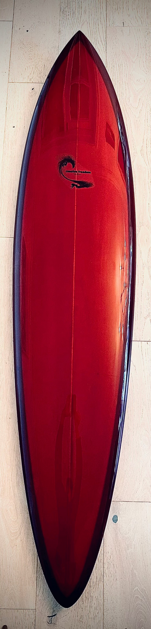 Red surfboard with a logo on a wooden floor