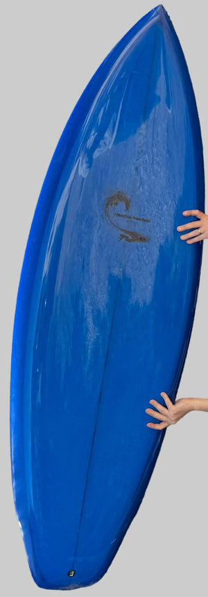 Blue surfboard held by a person against a gray background