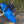 Person holding a blue kayak on a rocky path with trees in the background